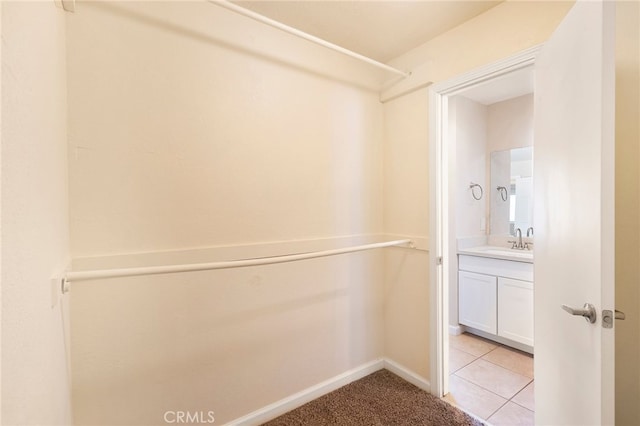 walk in closet featuring sink and light tile patterned floors