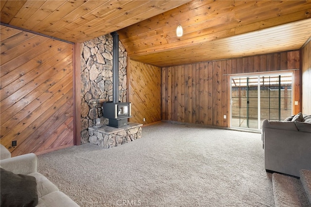 living room with wooden walls, wooden ceiling, carpet, a wood stove, and vaulted ceiling