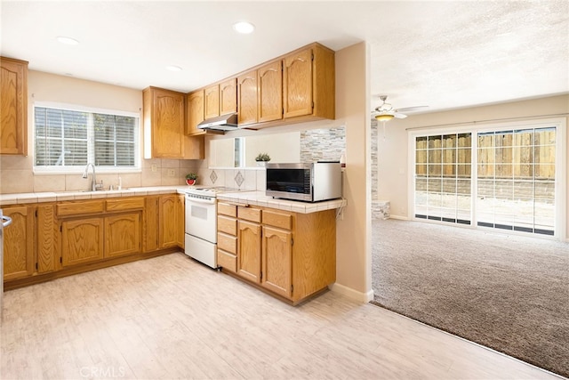 kitchen featuring tile counters, white electric range oven, sink, and tasteful backsplash