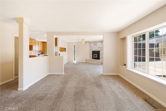 unfurnished living room with ceiling fan, light carpet, and a fireplace