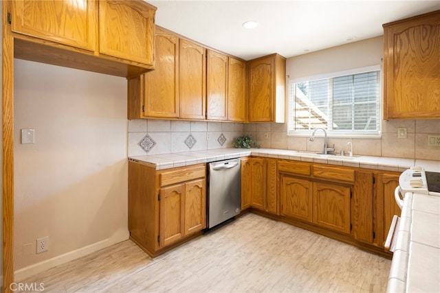 kitchen featuring tile countertops, stainless steel dishwasher, backsplash, and sink