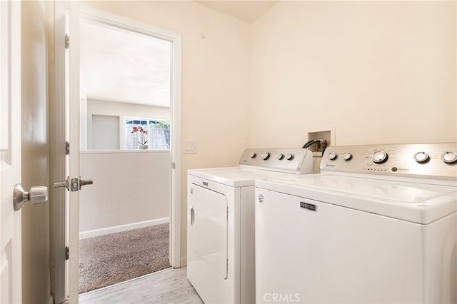 clothes washing area with washing machine and clothes dryer and light hardwood / wood-style flooring