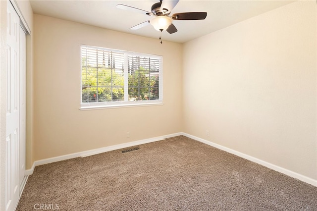 empty room featuring ceiling fan and carpet