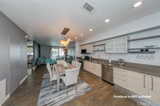 kitchen featuring appliances with stainless steel finishes, dark hardwood / wood-style floors, pendant lighting, and sink