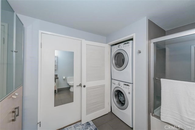 washroom featuring dark tile patterned flooring and stacked washer and clothes dryer