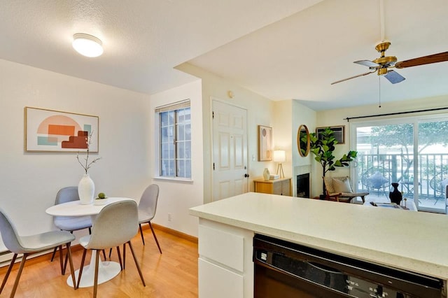 kitchen featuring ceiling fan, light wood-type flooring, white cabinetry, a textured ceiling, and black dishwasher