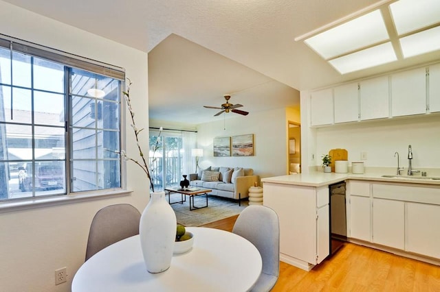 kitchen with kitchen peninsula, dishwasher, sink, white cabinets, and light hardwood / wood-style floors