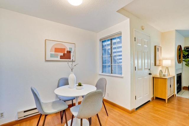 dining space with baseboard heating and light wood-type flooring