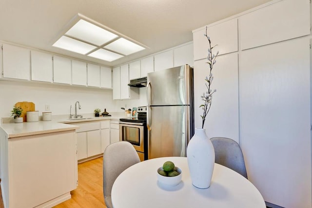 kitchen featuring appliances with stainless steel finishes, sink, white cabinets, and light hardwood / wood-style flooring