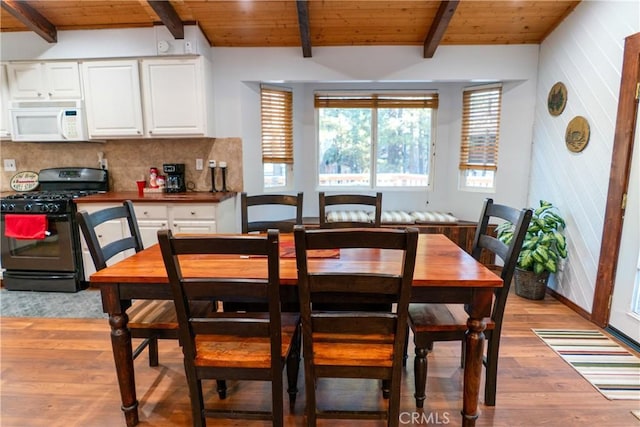 dining room featuring beam ceiling, wooden ceiling, and light wood-type flooring