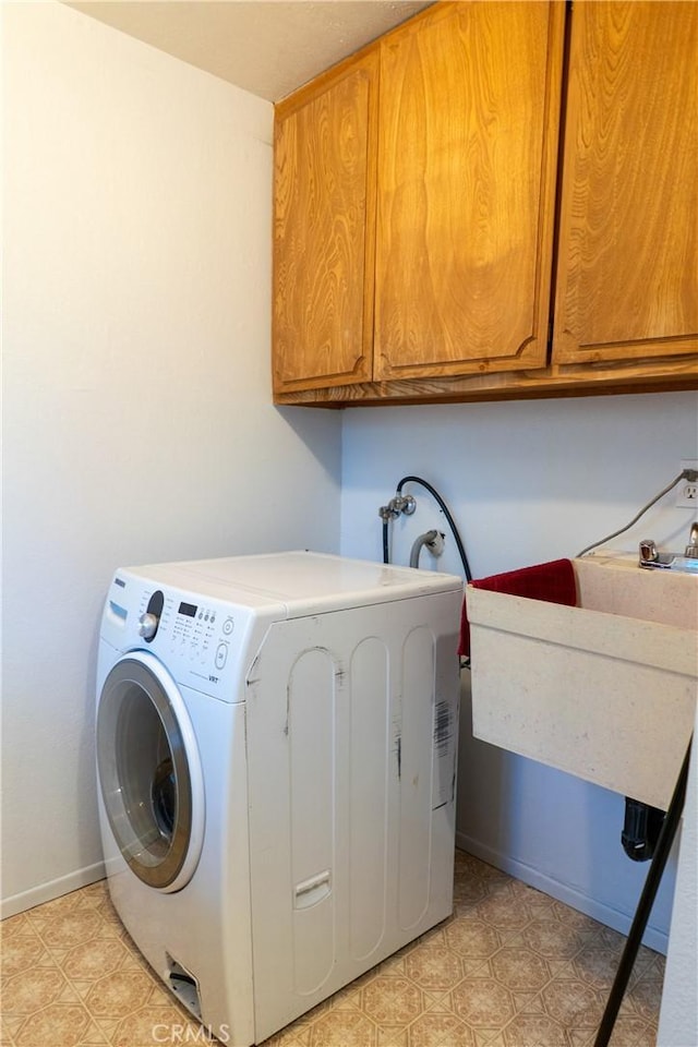 clothes washing area featuring washer / clothes dryer and cabinets