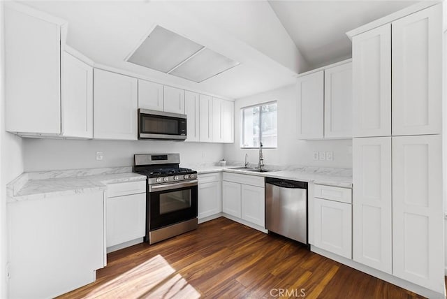 kitchen with sink, dark hardwood / wood-style floors, light stone countertops, appliances with stainless steel finishes, and white cabinetry