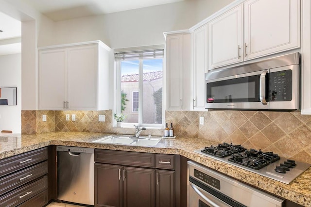 kitchen with appliances with stainless steel finishes, white cabinetry, dark brown cabinetry, and sink