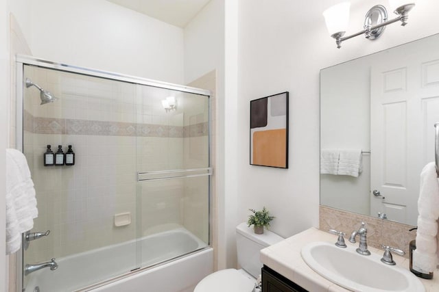 full bathroom featuring toilet, bath / shower combo with glass door, and vanity