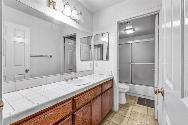 full bathroom featuring combined bath / shower with glass door, vanity, tile patterned floors, and toilet