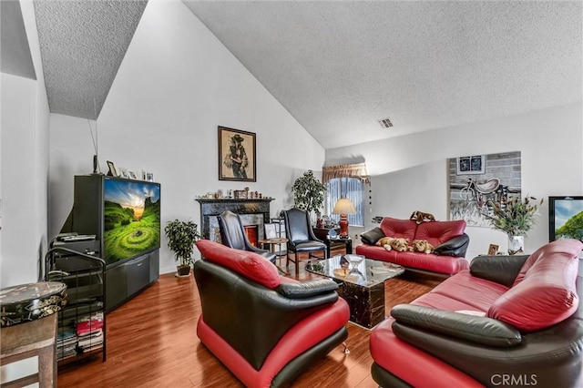 living room with hardwood / wood-style floors, a textured ceiling, and lofted ceiling