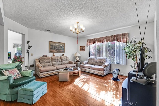 living room featuring an inviting chandelier, a textured ceiling, and hardwood / wood-style flooring