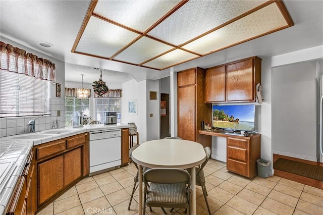 kitchen with dishwasher, sink, tasteful backsplash, tile countertops, and a textured ceiling