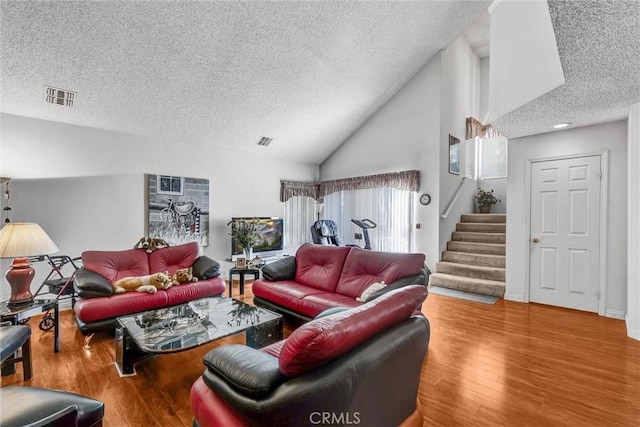 living room with lofted ceiling, hardwood / wood-style floors, and a textured ceiling