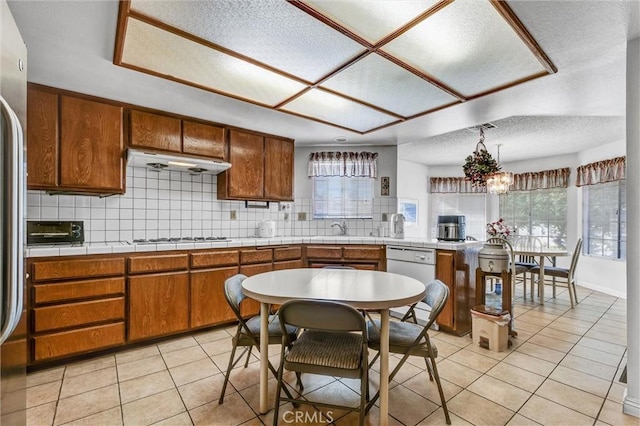 kitchen featuring tile countertops, dishwasher, pendant lighting, backsplash, and a textured ceiling