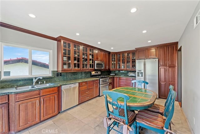 kitchen with decorative backsplash, dark stone counters, stainless steel appliances, sink, and light tile patterned floors