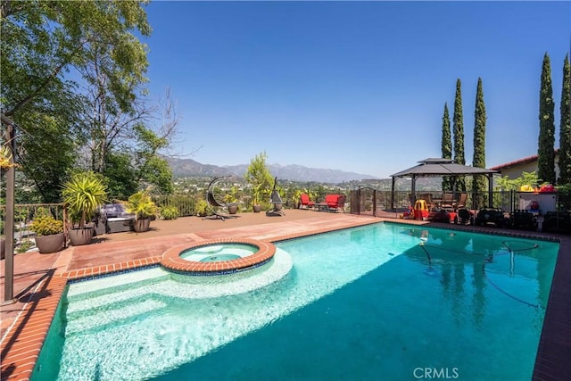 view of swimming pool with a gazebo, a patio area, a mountain view, and an in ground hot tub