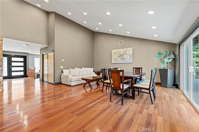 dining room featuring light wood-type flooring and high vaulted ceiling