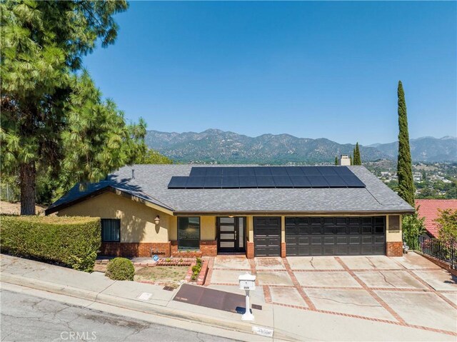 view of front facade with a mountain view, a garage, and solar panels