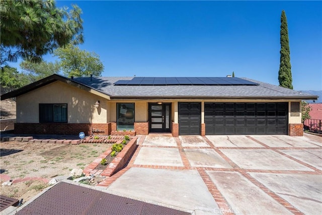 ranch-style home with a garage and solar panels