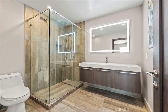 bathroom featuring vanity, a shower with shower door, and toilet