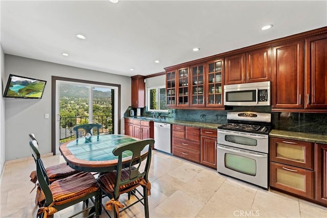 kitchen featuring sink, stainless steel appliances, dark stone counters, and tasteful backsplash