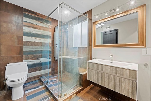 bathroom with walk in shower, vanity, tile walls, tile patterned flooring, and toilet