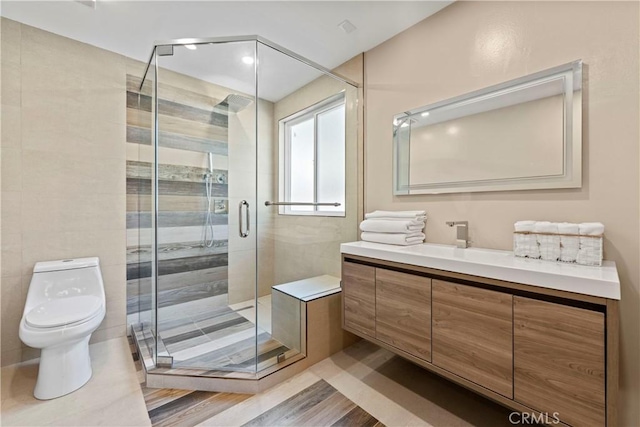 bathroom with hardwood / wood-style floors, vanity, toilet, and a shower with shower door