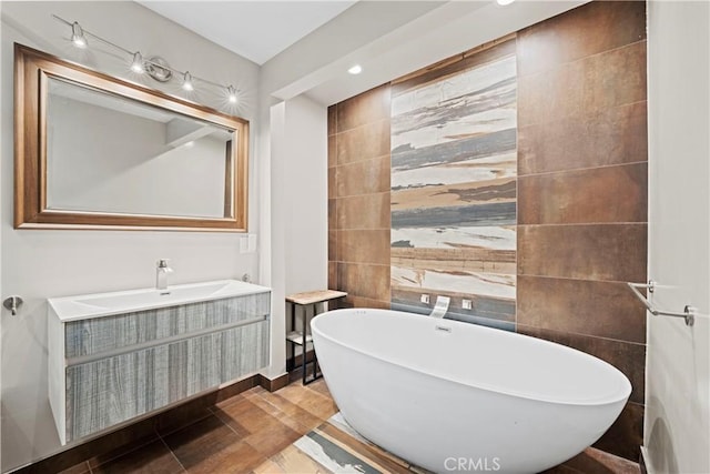 bathroom featuring a washtub, vanity, and tile walls