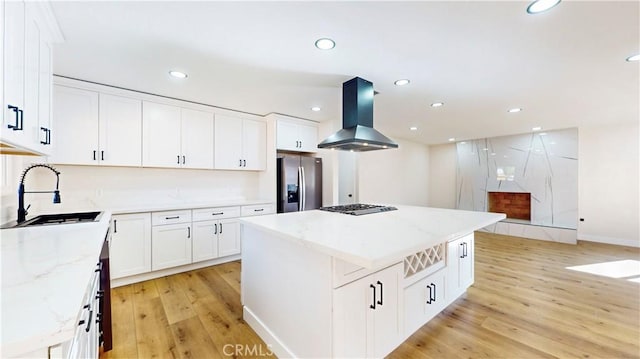 kitchen with island exhaust hood, stainless steel appliances, sink, white cabinets, and a center island