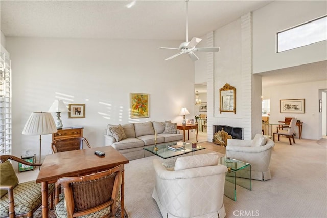 living room featuring a brick fireplace, light colored carpet, ceiling fan, and a high ceiling