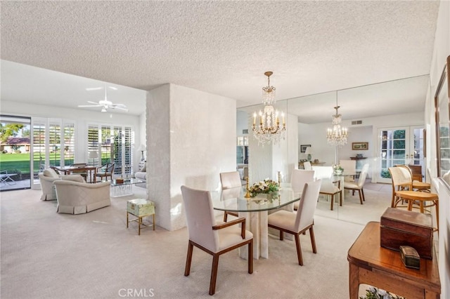 dining area with light carpet, visible vents, a textured ceiling, and ceiling fan with notable chandelier