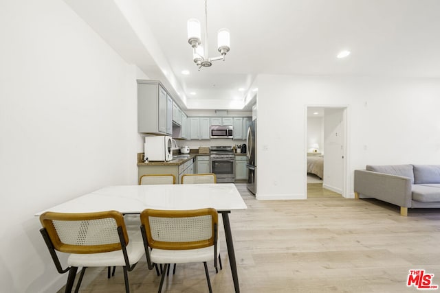 dining area featuring sink, a notable chandelier, and light wood-type flooring