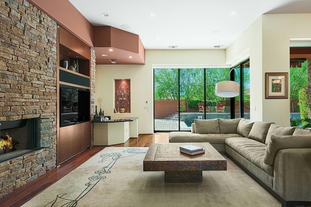 living room featuring a stone fireplace and light hardwood / wood-style flooring