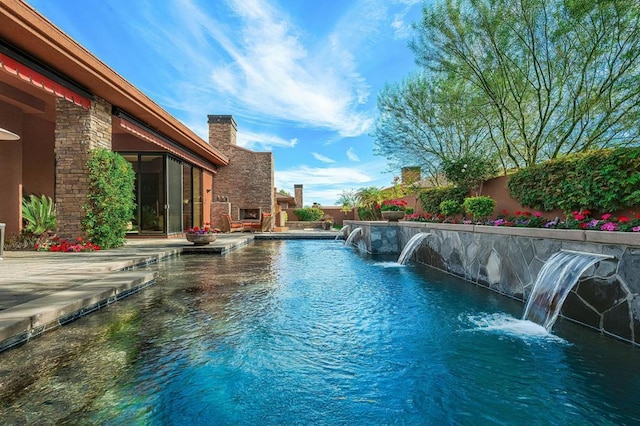 view of swimming pool featuring a patio area, pool water feature, and exterior fireplace