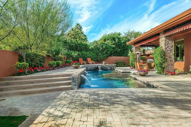 view of pool featuring pool water feature, a patio, and a hot tub