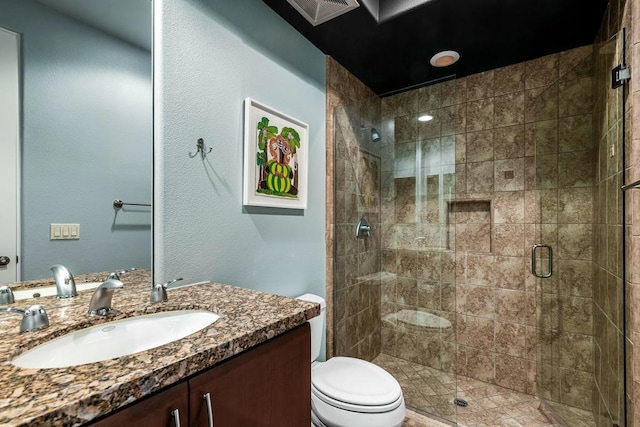 bathroom with vanity, toilet, and a shower with door