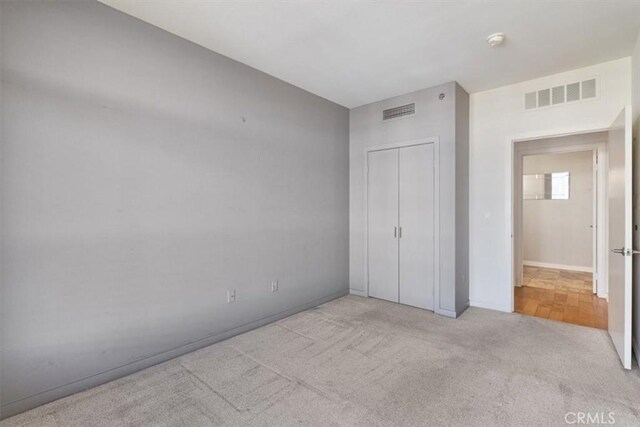 unfurnished bedroom with light colored carpet and a closet