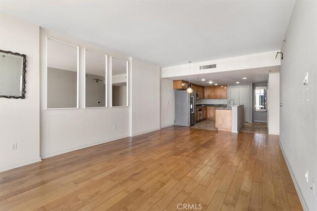 unfurnished living room featuring light wood-type flooring and sink