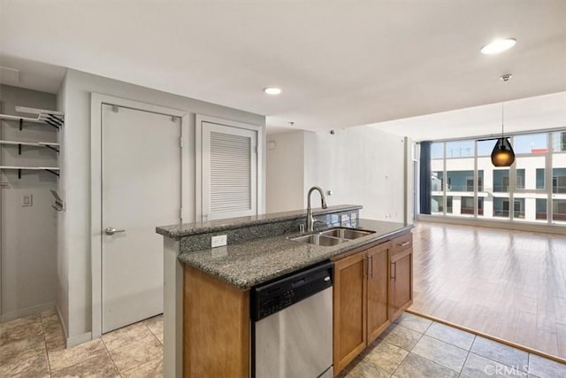 kitchen featuring pendant lighting, stainless steel dishwasher, sink, a wall of windows, and dark stone counters