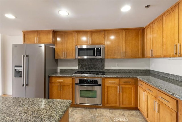 kitchen with decorative backsplash, appliances with stainless steel finishes, and dark stone countertops