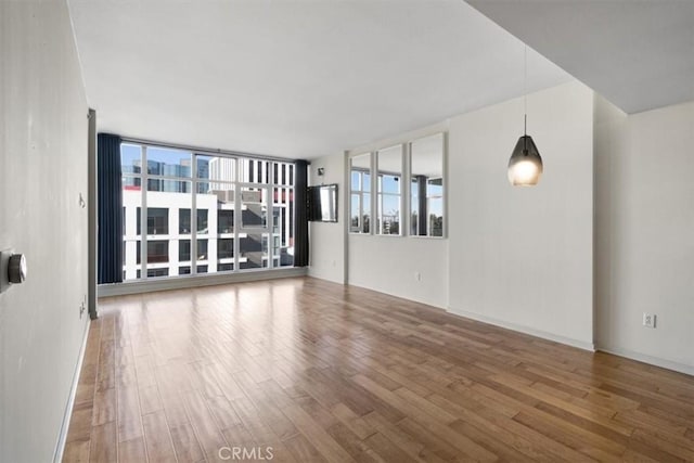 empty room featuring floor to ceiling windows and wood-type flooring