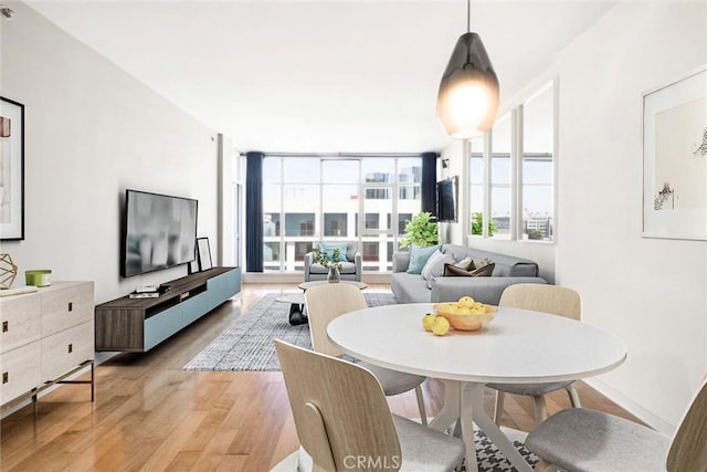 dining space with a wall of windows and light hardwood / wood-style floors