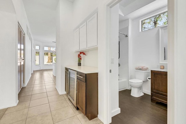 interior space with light tile patterned floors, white cabinetry, beverage cooler, and a healthy amount of sunlight