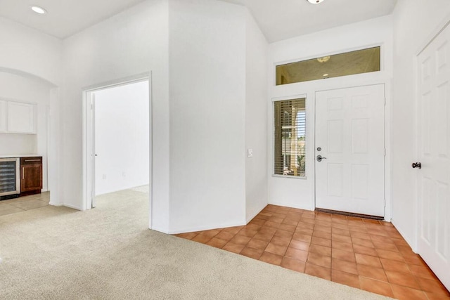 foyer featuring beverage cooler and light colored carpet